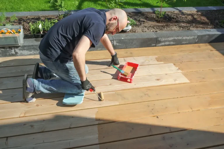 Un homme qui applique un produit sur une terrasse en bois