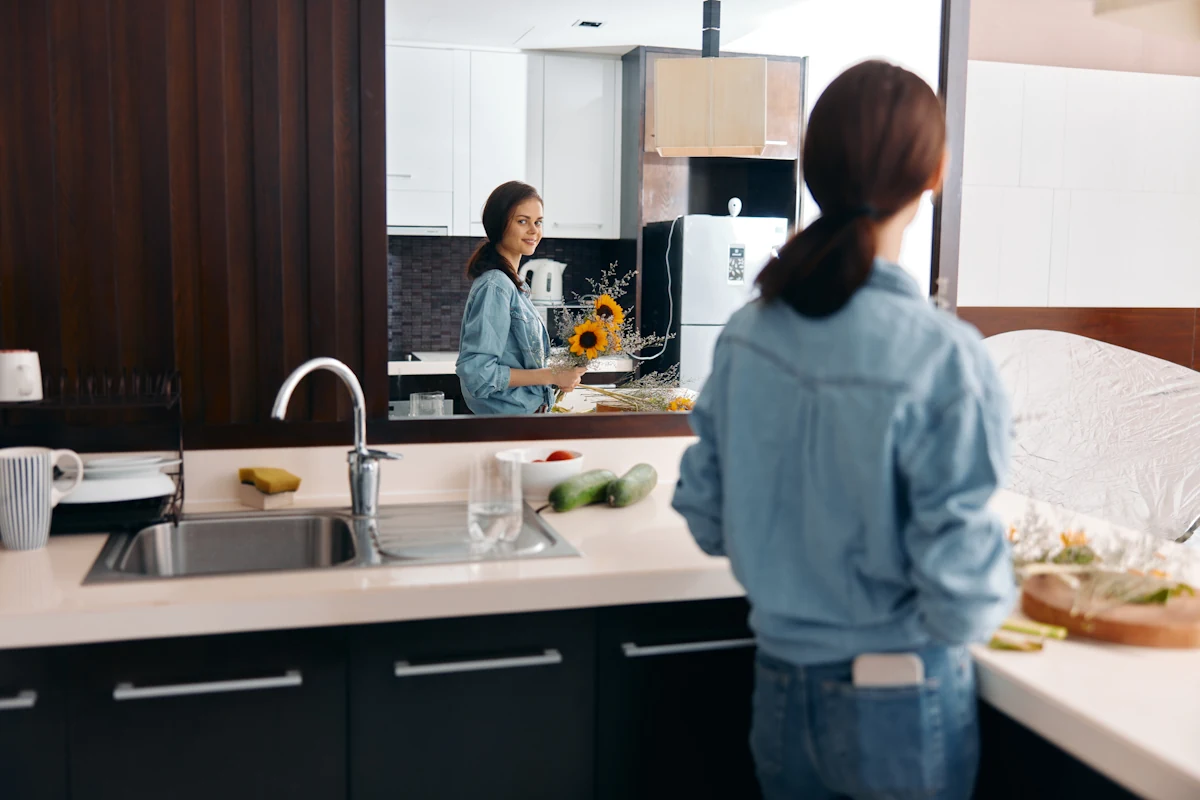 Une femme dans une cuisine qui se regarde dans un miroir