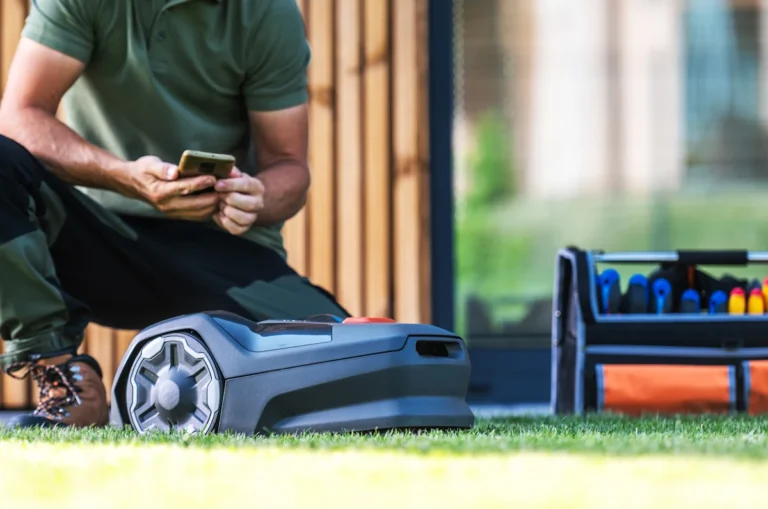 Un homme qui regarde son téléphone à côté d'un robot tondeuse