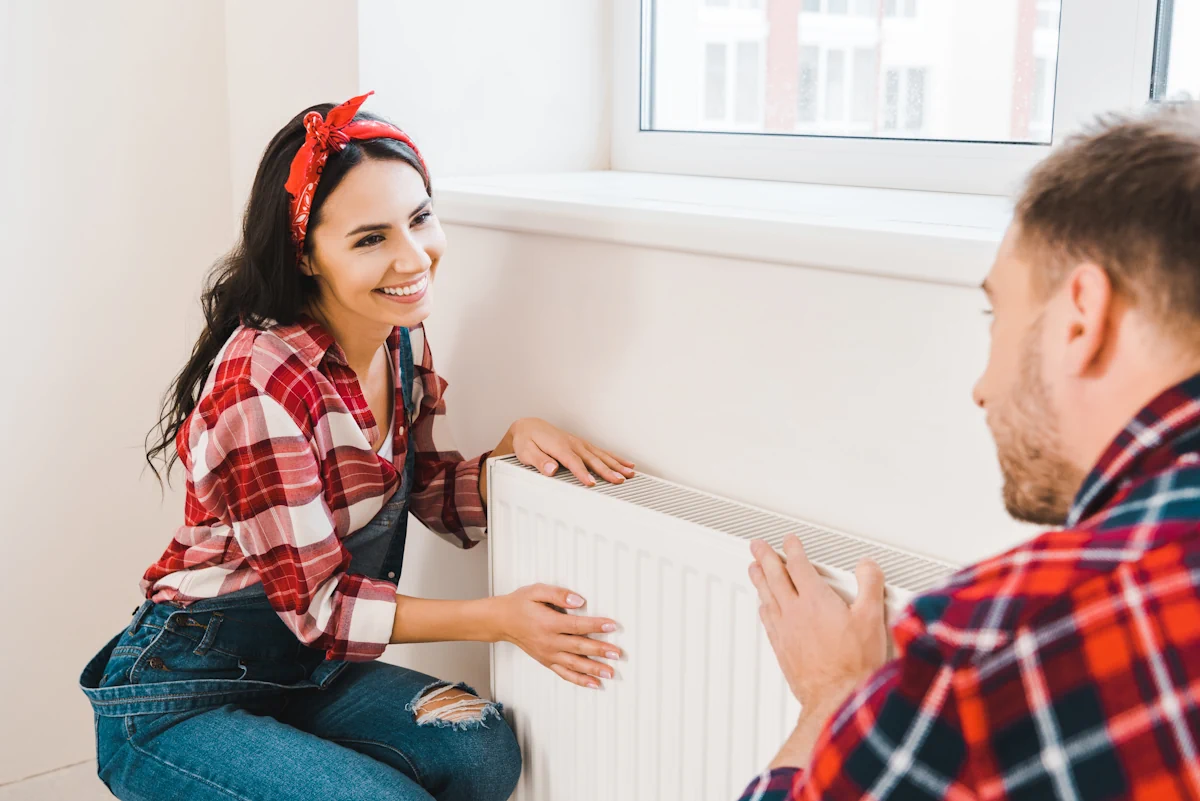 Un homme et une femme qui tiennent un radiateur blanc contre un mur