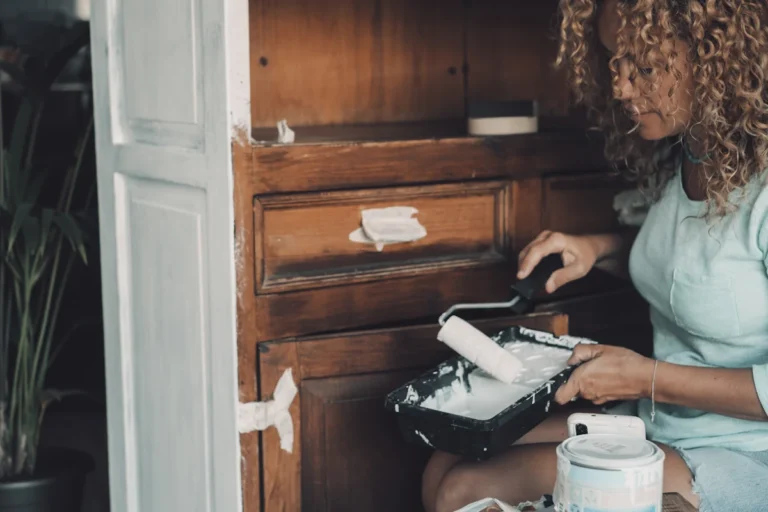 Une femme qui peint un meuble en bois en blanc